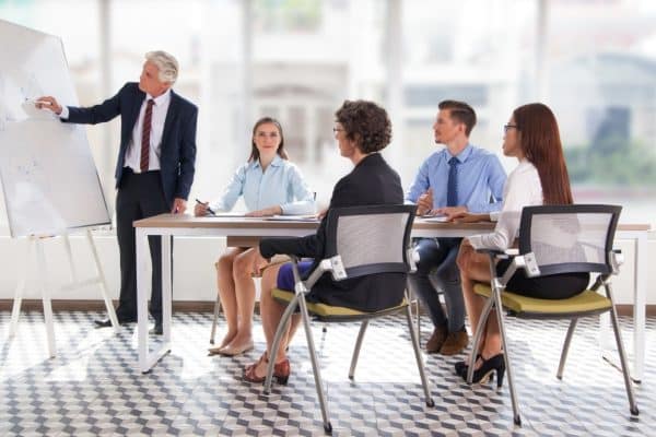 Business team discussing diagram on whiteboard. Business executives listening to presentation of senior colleague. Business meeting concept